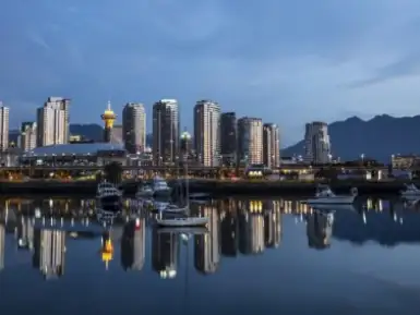Downtown Vancouver reflecting off the glass-like surface of False Creek early in the morning. The North Shore Mountains are in the background.