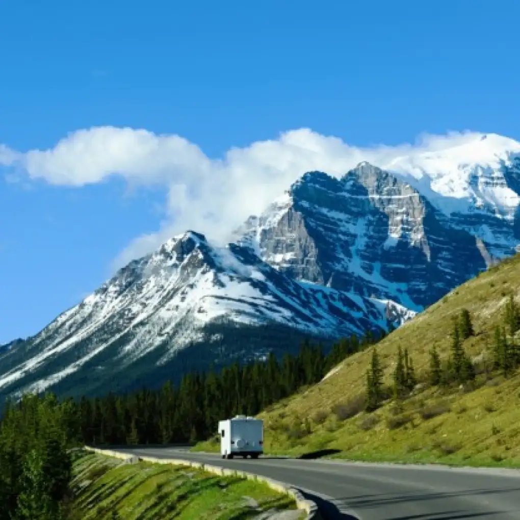 A motorhome drives past a snowy mountain peak