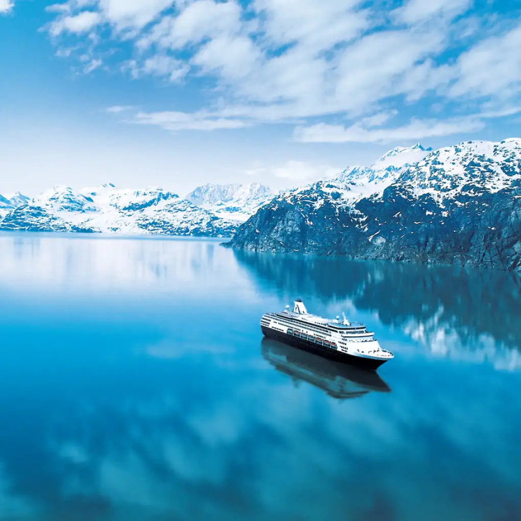 Cruise ship floats near a snowy mountain backdrop