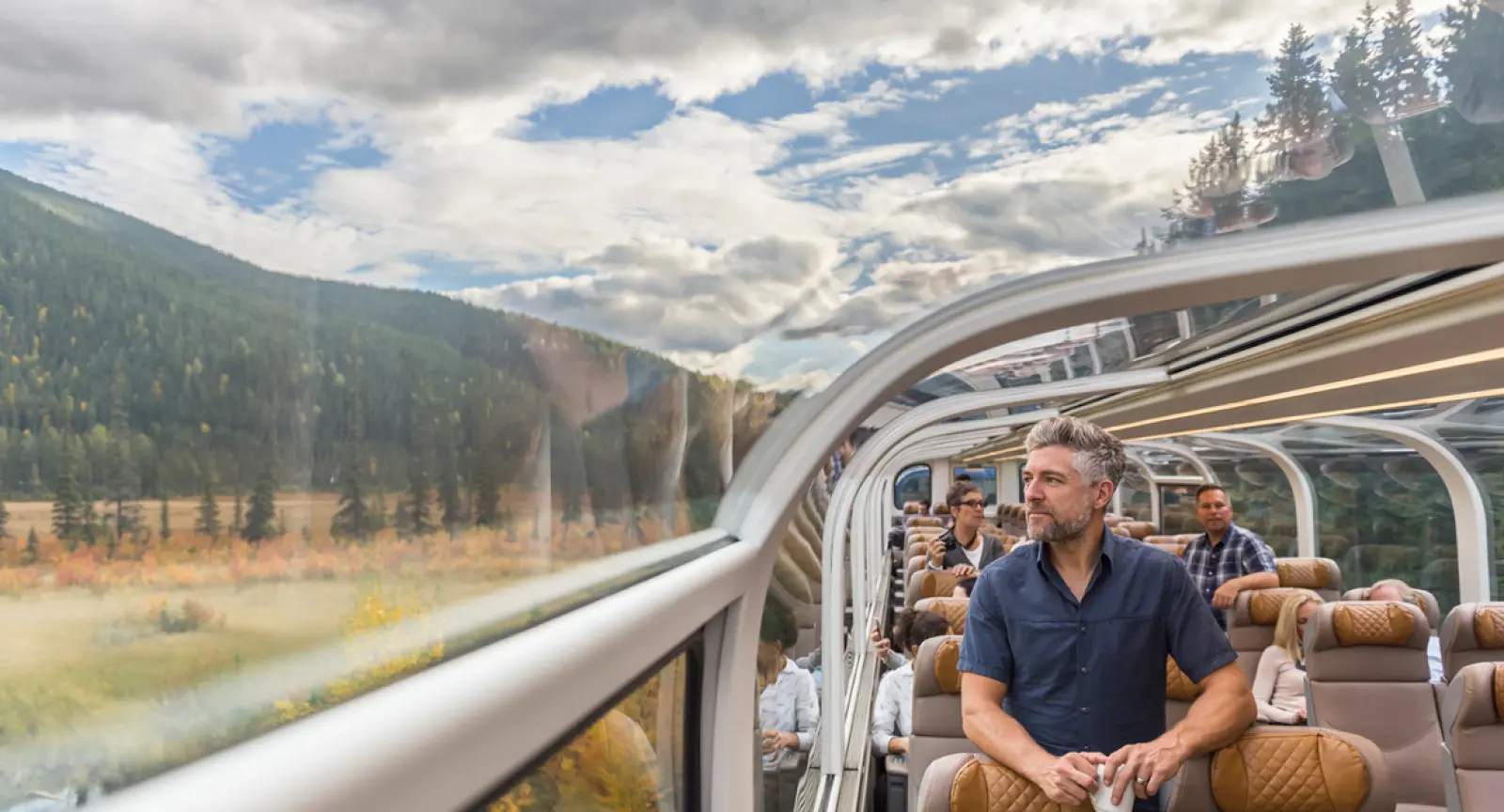 Man enjoys the view of Canada through a rocky mountaineer train window