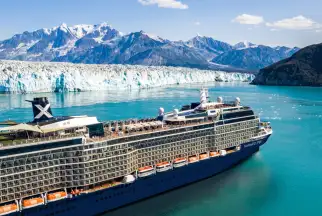 Celebrity cruise ship floats just offshore from a glacier
