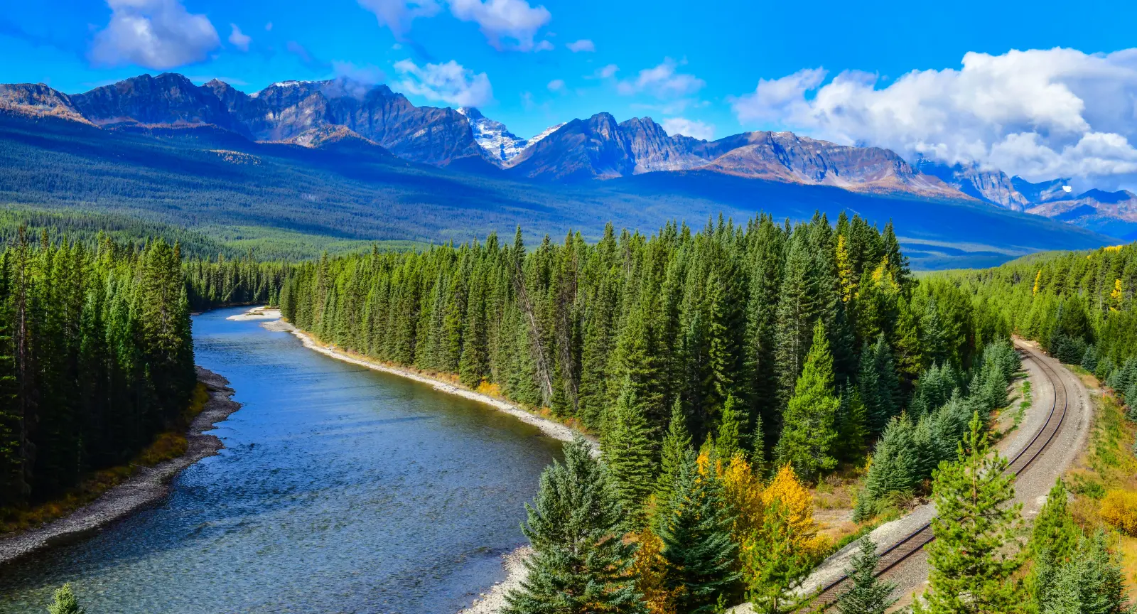 A railway and a river stretch off towards a mountain range