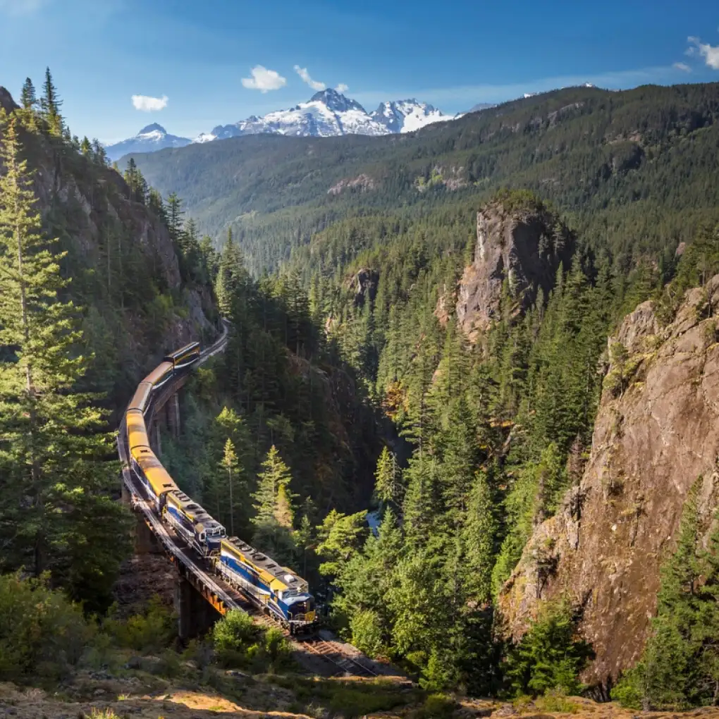 Rocky Mountaineer train winds through a forested mountain valley