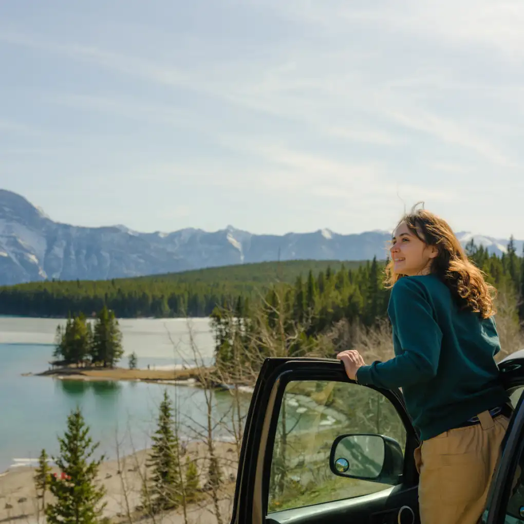 a woman looks out over a Canadian landscape from her car