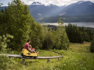 Father and son are riding the Pipe Mountain Coaster at Revelstoke Mountain Resort